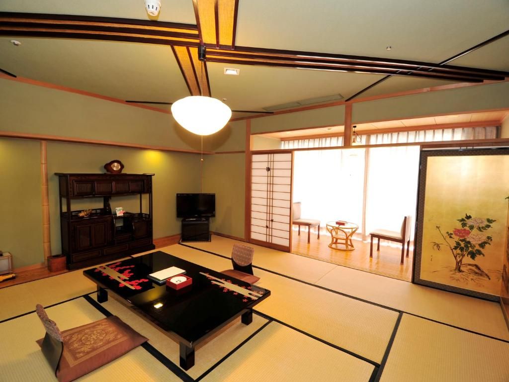 Una habitación japonesa tradicional con suelo de tatami, una mesa baja y puertas correderas que dan a un espacio exterior.