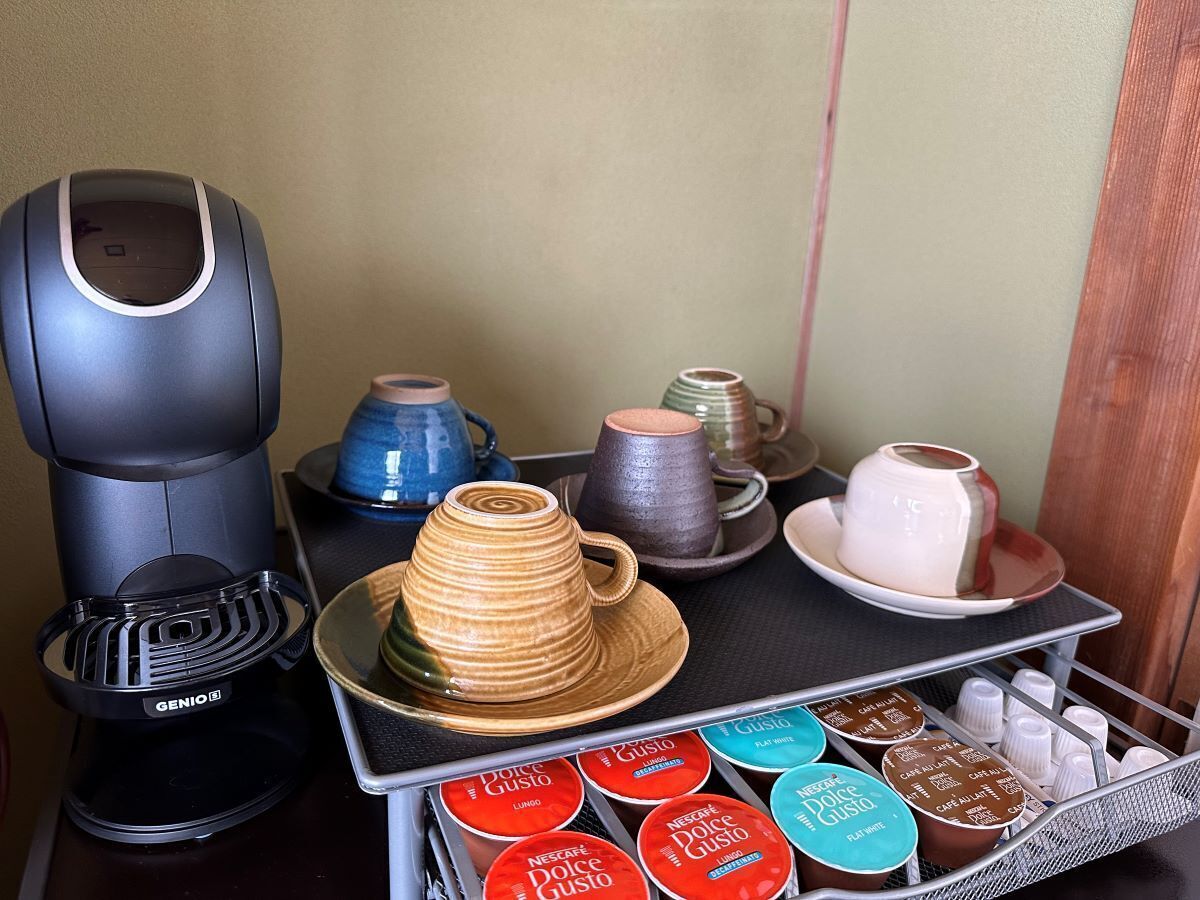 A coffee machine, a stack of cups, and a tray with coffee pods.