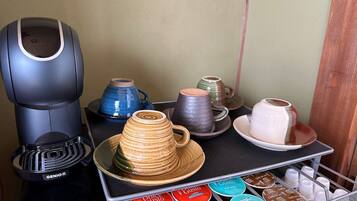A coffee machine, a stack of cups, and a tray with coffee pods.