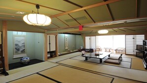 Une pièce de style japonais traditionnel, avec un sol recouvert de tatamis, une table basse, des portes coulissantes et un téléviseur.
