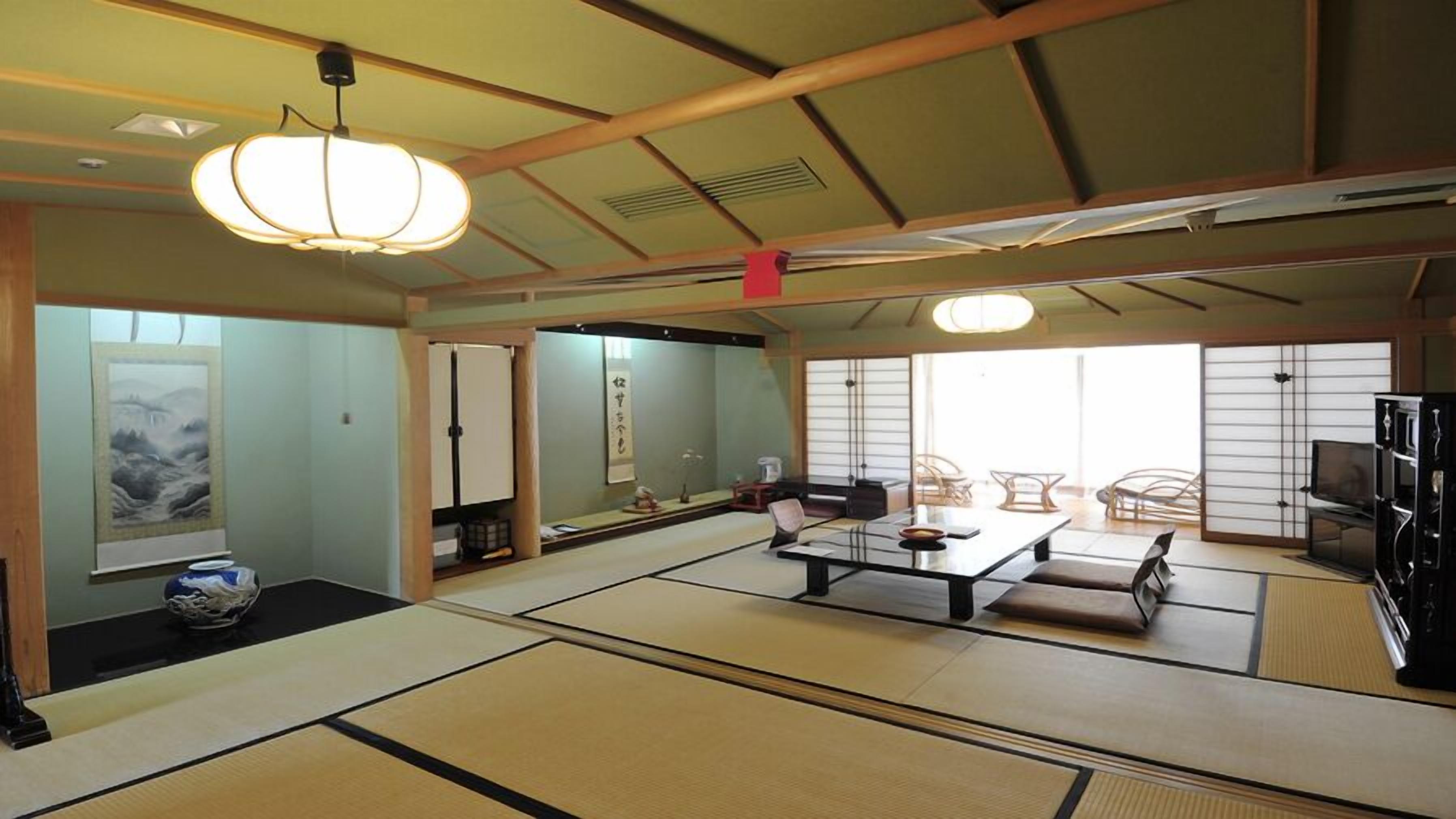 Une pièce de style japonais traditionnel, avec un sol recouvert de tatamis, une table basse, un canapé et un téléviseur.