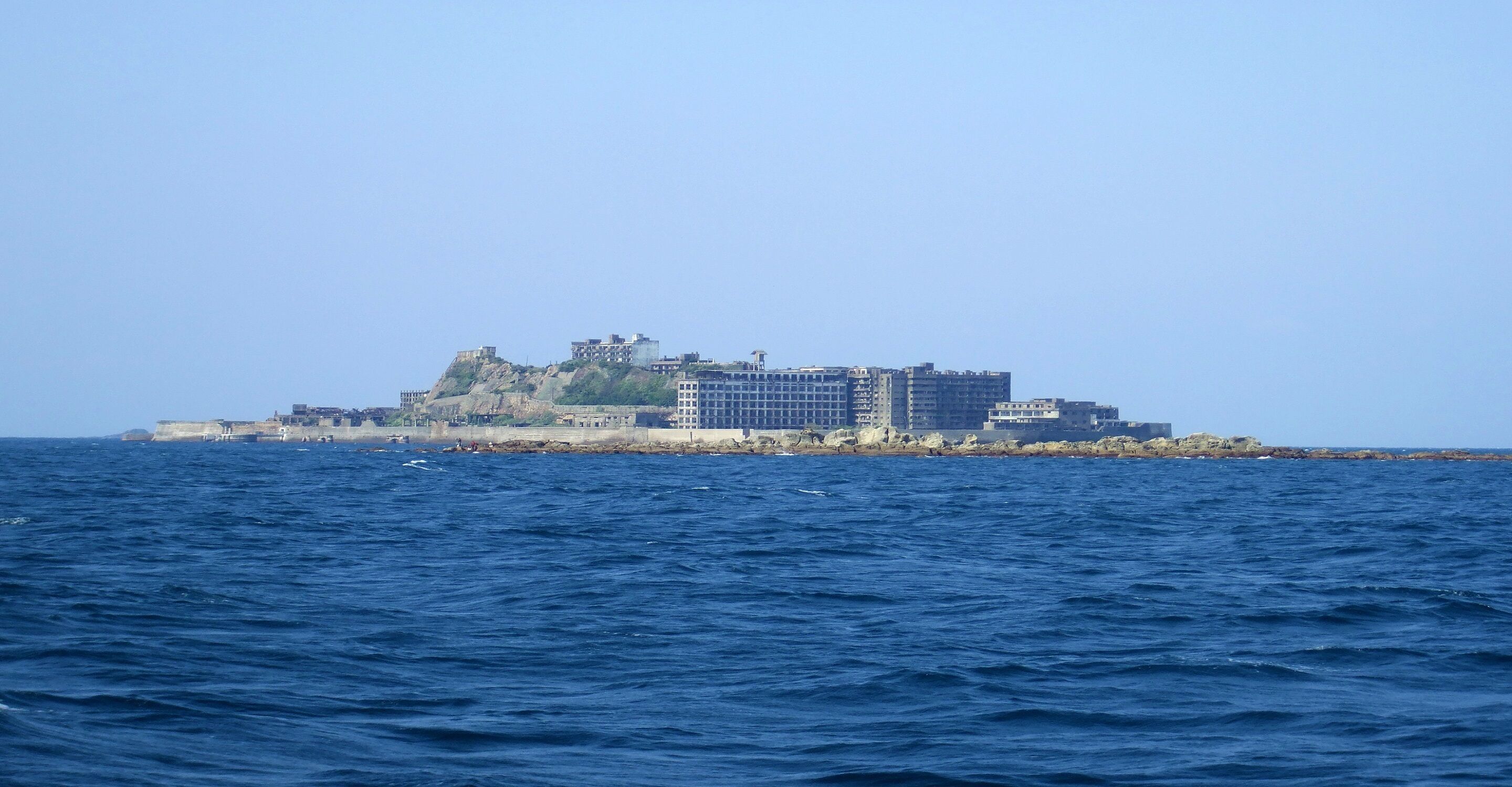 Un hotel costero con varias edificaciones, incluyendo una estructura destacada en una colina y otras más bajas a lo largo de la costa.