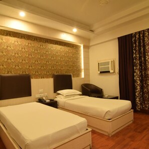 A hotel room with two beds, a desk, a chair, a telephone, and an air conditioning unit.