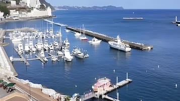 A marina with multiple boats docked, a pier, and a building with a red roof.