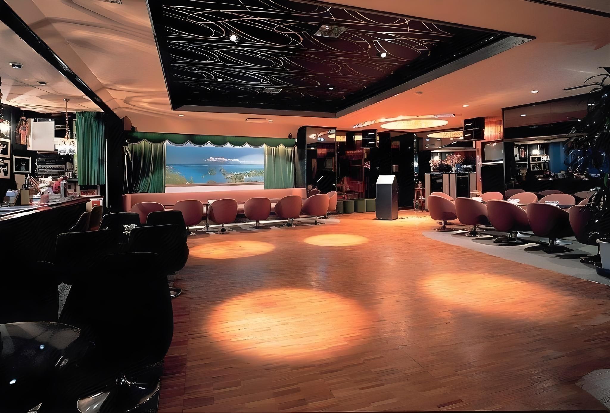 A modern interior with a bar area, seating, and a view of the sea.