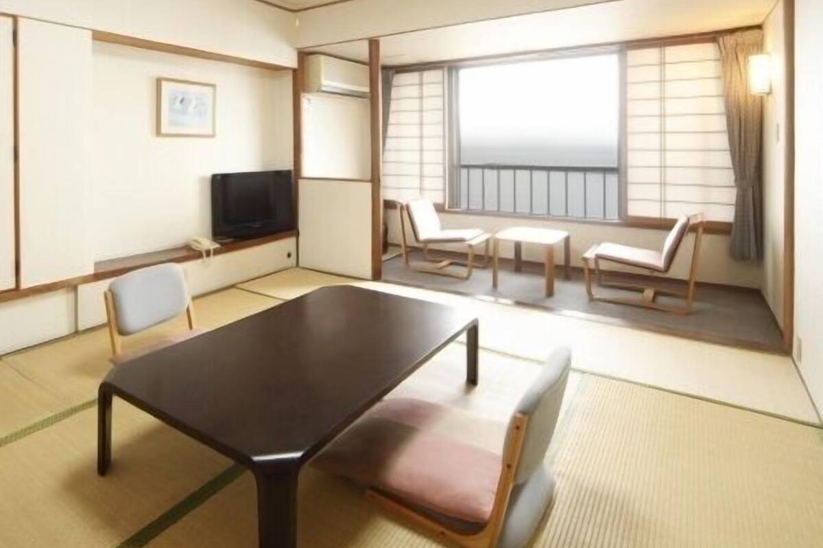 Ein Hotelzimmer mit Bett, Fernseher, Esstisch und einem Balkon mit Blick.