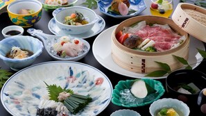 A variety of dishes and food items on a table, including a bowl of sashimi, a bowl of soup, and a bamboo steamer with meat. - Yufunogo Saigakukan (Yufu)