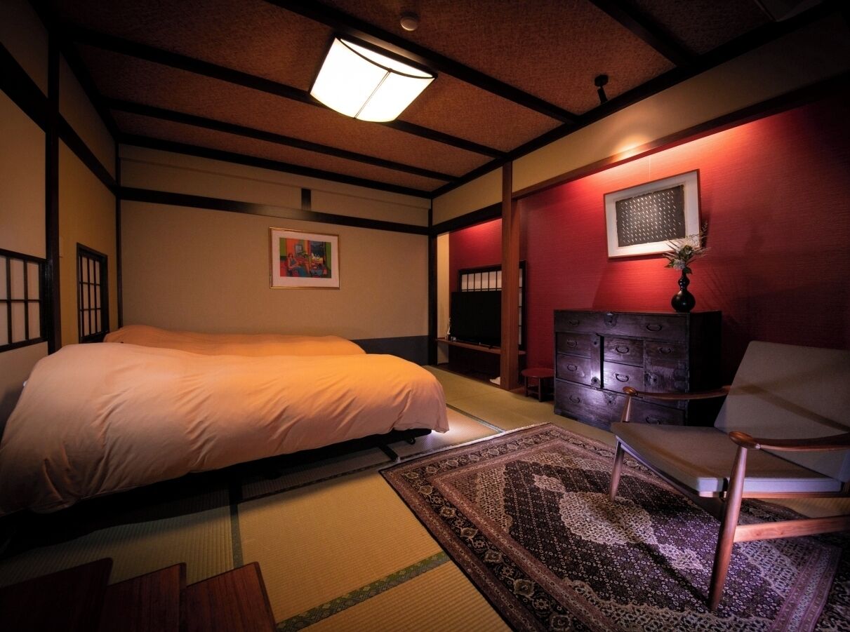 Een traditionele Japanse kamer met tatami vloeren, een bed, een houten kast en een televisie.