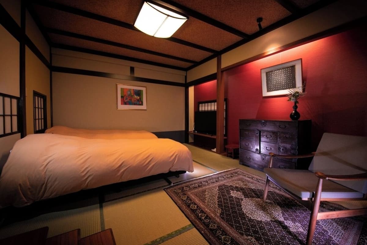 Une pièce de style japonais traditionnel, avec un sol recouvert de tatamis, un lit, une armoire en bois et un téléviseur.