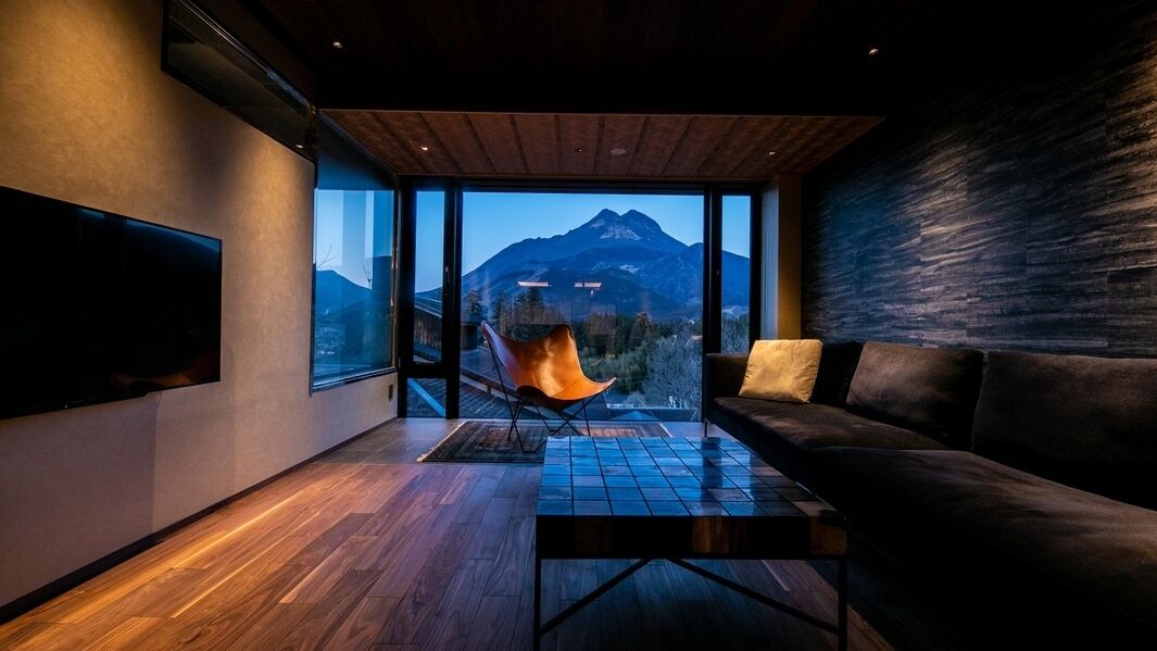 Een moderne woonkamer met een groot raam, een bank, een fauteuil en een flatscreen-tv.