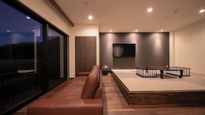 Ein modernes Wohnzimmer mit einer Ledersofa, einem Holztisch und einem flachbildfernseher an der Wand.