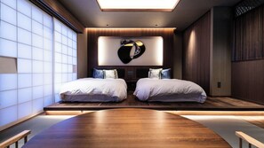 Un dormitorio moderno con dos camas, una mesa de madera grande y una obra de arte original en la pared.