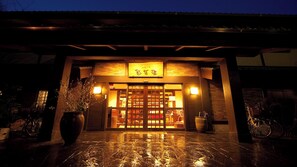 A traditional Japanese building entrance with a tiled floor, wooden doors, and a sign with Japanese characters. - Yufunogo Saigakukan (Yufu)