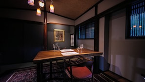 Een eethoek met een houten tafel, stoelen en een kunstwerk in een lijst aan de muur.
