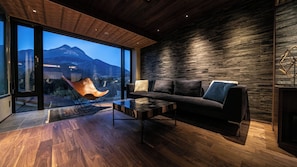 A modern living room with a large window, a sofa, a coffee table, and a unique chair. - Yufunogo Saigakukan (Yufu)
