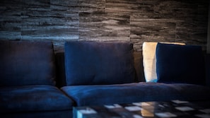 A sectional sofa with a textured wall behind it. - Yufunogo Saigakukan (Yufu)
