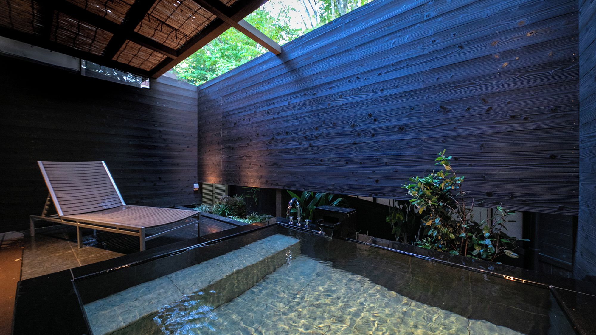A modern interior with a wooden wall, a glass pool, and a lounge chair.