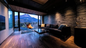 Een modern interieur met een groot raam, een bank, een stoel en een geometrisch sculptuur.