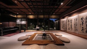 Un interior japonés tradicional con suelo de tatami, una mesa de madera baja y caligrafía en las paredes.