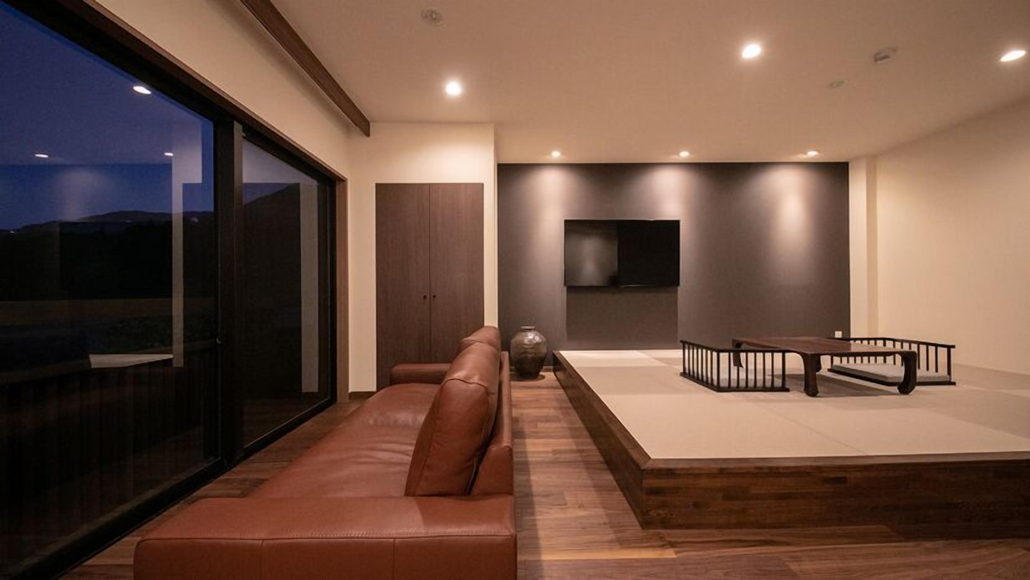 Een moderne woonkamer met een leren bank, een houten salontafel en een flatscreen televisie aan de muur.