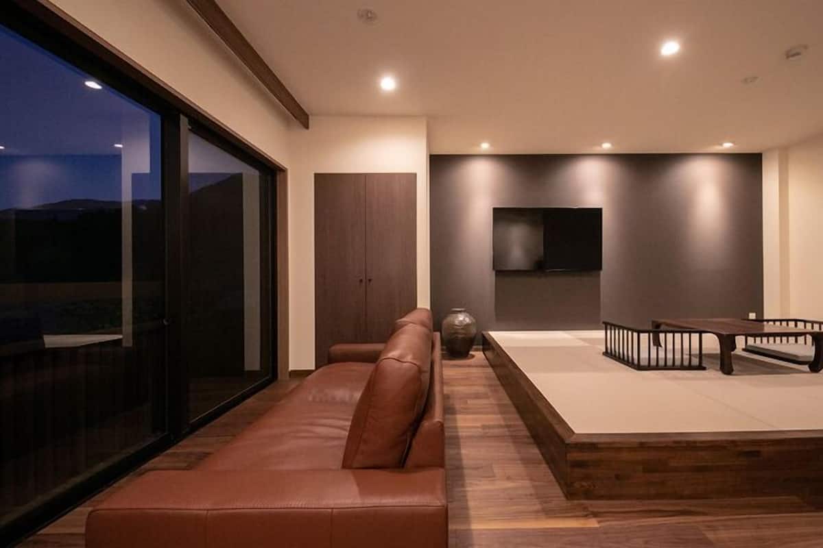 Un salon moderne avec un canapé en cuir, une table basse en bois et un téléviseur à écran plat fixé au mur.
