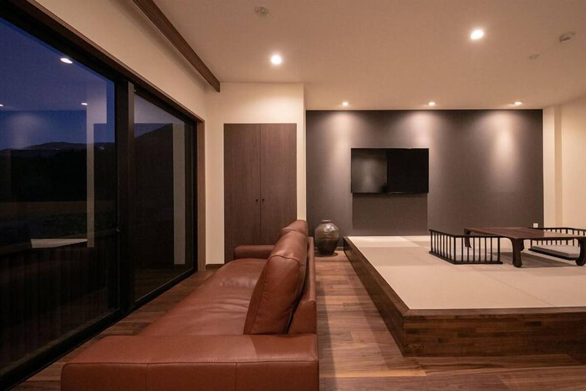 Ein modernes Wohnzimmer mit einer Ledersofa, einem Holztisch und einem an der Wand befestigten Flachbildfernseher.