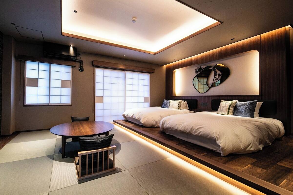 Une chambre d’hôtel moderne dotée d’un grand lit, d’une table à manger et offrant une vue sur la ville grâce à de grandes fenêtres.