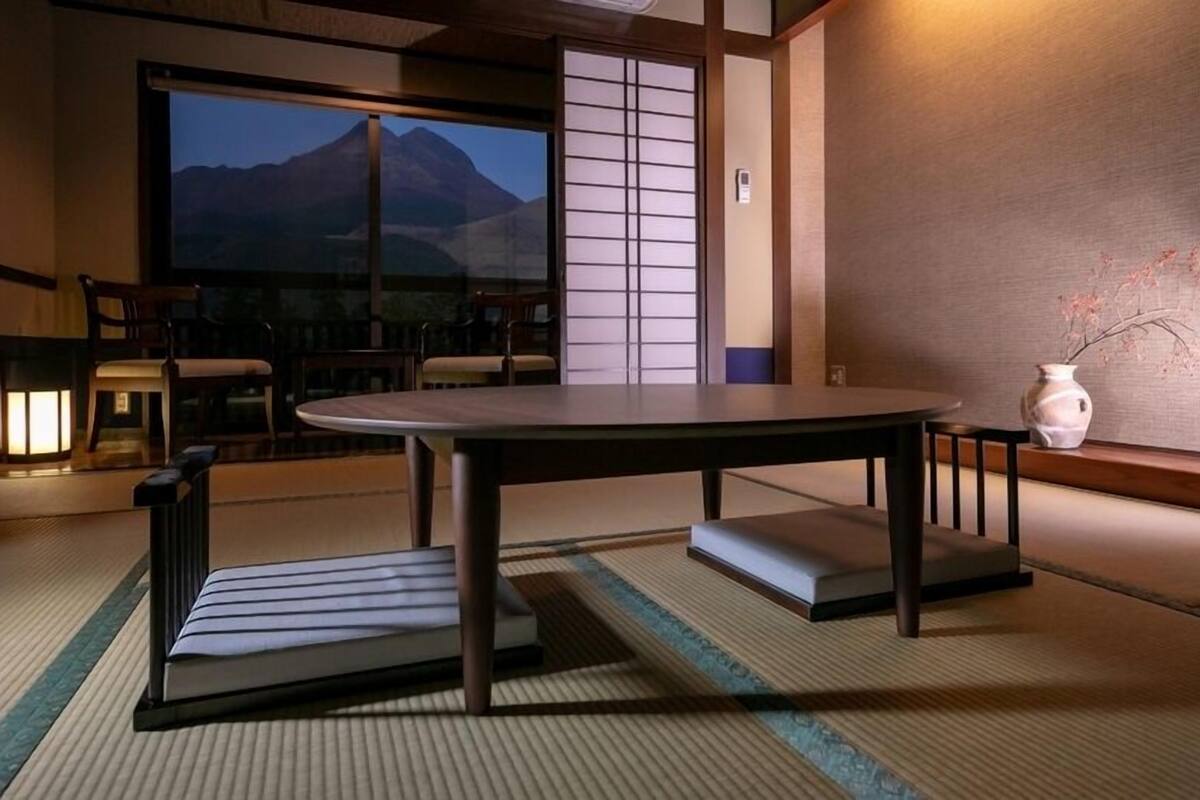 Une pièce de style japonais traditionnel, avec un sol recouvert de tatamis, une table basse et une vue sur une montagne.
