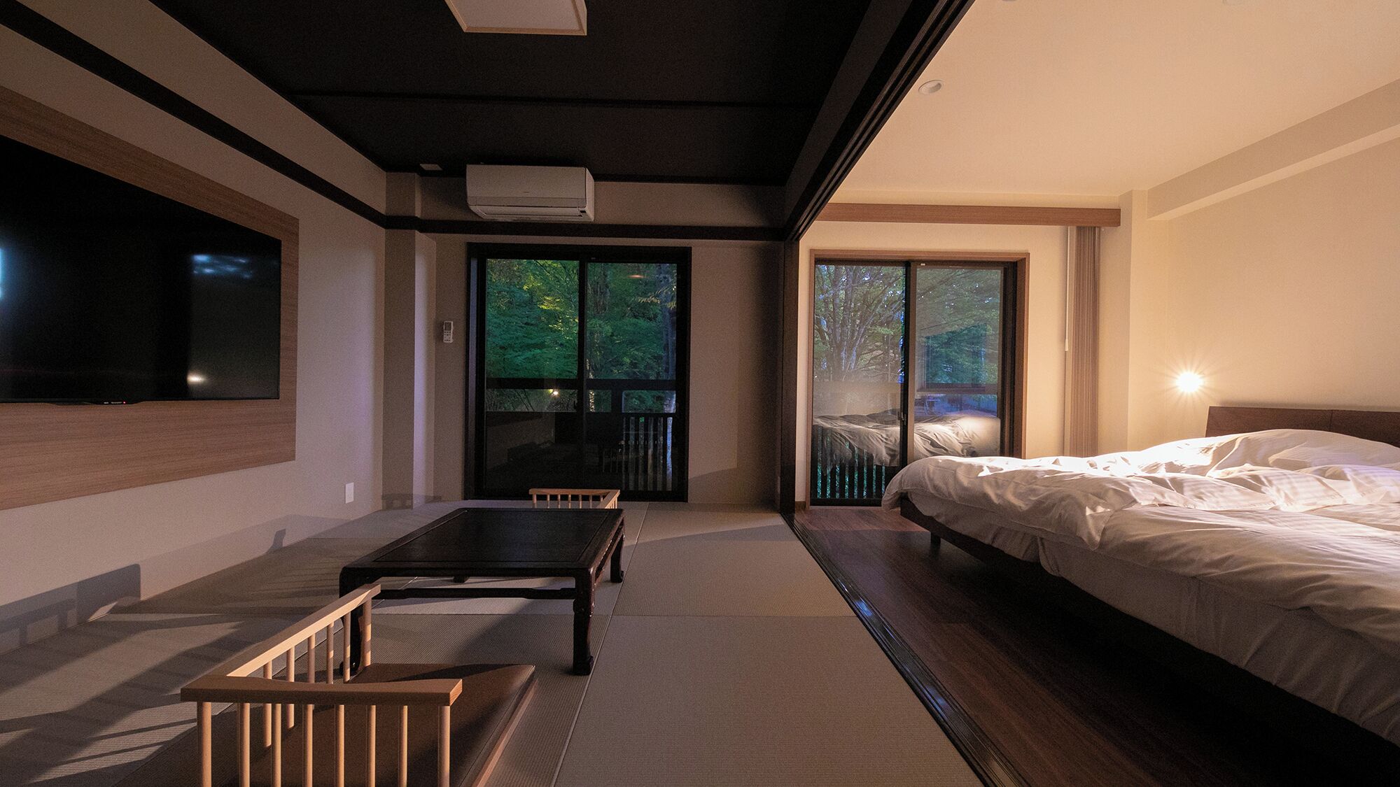 Een moderne slaapkamer met een bed, een televisie en een schuifglazen deur naar een balkon.