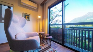 A modern room with a large window, a high-backed chair, a small table, and a rug. - Yufunogo Saigakukan (Yufu)