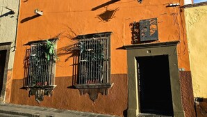 Ein Gebäude mit einer braunen Fassade, einer schwarzen Tür und vergitterten Fenstern.
