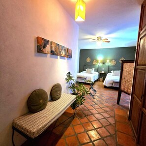 Habitación de hotel con cama, reposabajares y una pared con obras de arte.