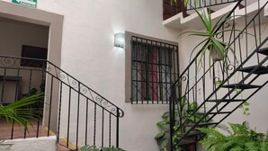 Eine Treppe mit Metallgeländern, ein Fenster mit Gitterstäben und ein Schild, das eine Fluchtroute kennzeichnet.