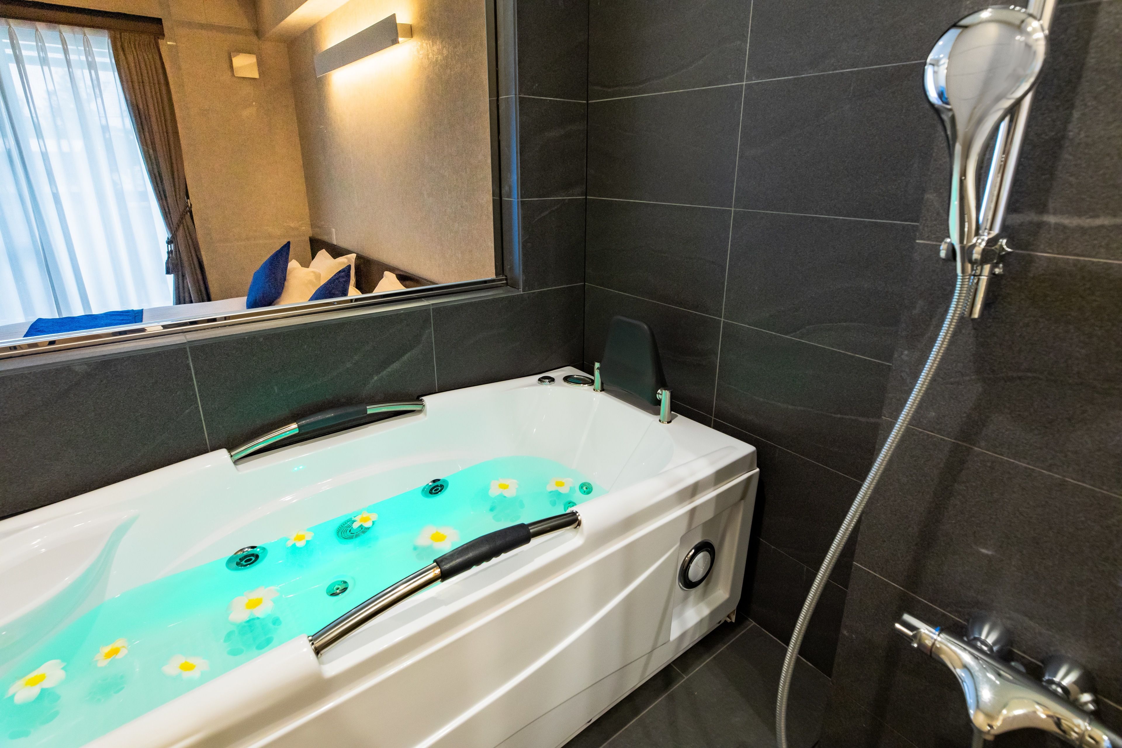 A modern bathroom with a bathtub, a shower, and a large mirror.