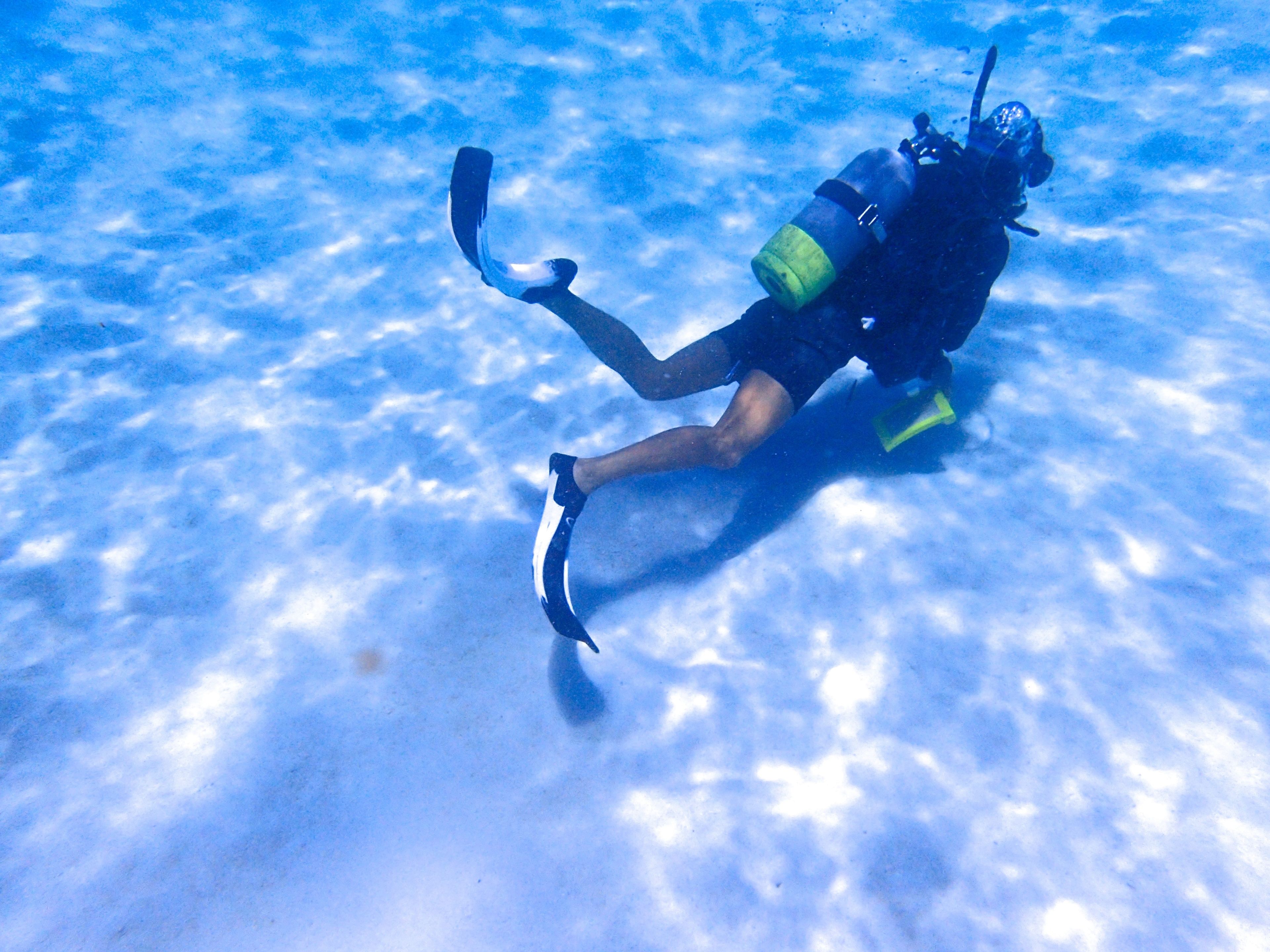 A diver underwater with fins and a scuba tank.