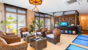 A modern living room with wicker furniture, a glass coffee table, and a television on a wooden stand. - Kerama Terrace (Tokashiki)