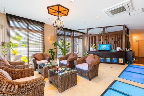 Una sala de estar moderna con muebles de mimbre, una mesa de centro de cristal y un televisor sobre un mueble de madera.