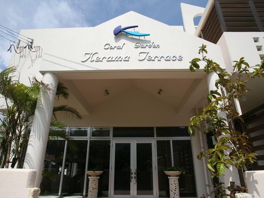A hotel entrance with a sign reading "Coral Garden Herama Terrace" and a modern architectural design.
