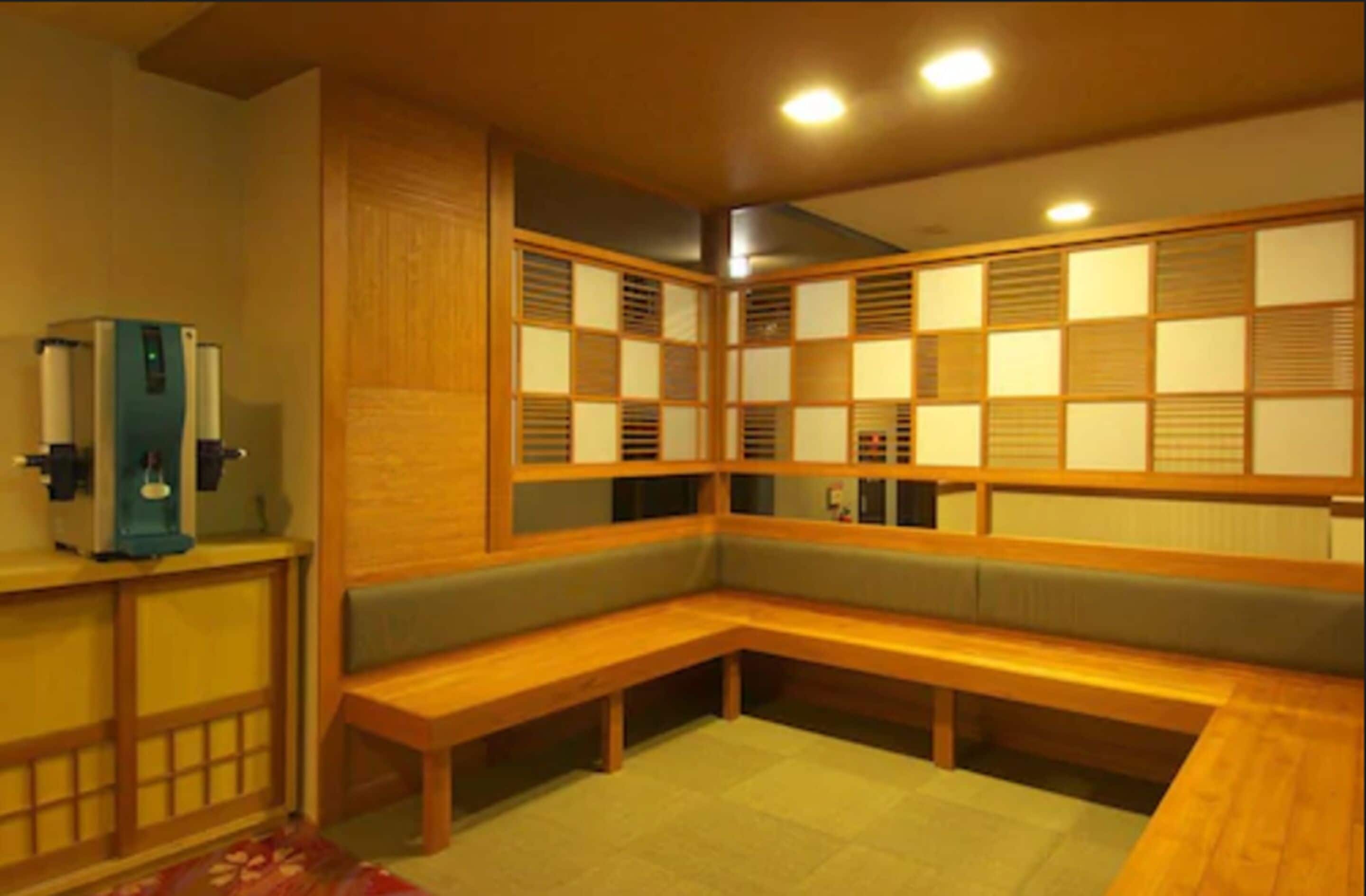 A traditional Japanese room with tatami flooring, a low wooden bench, and a water dispenser.