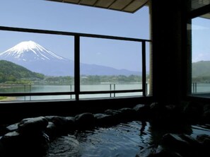 A room with a large window offering a view of a snow-capped mountain and a lake. - Hotel Mifujien (Fujikawaguchiko)
