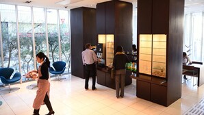 Et moderne interiør med store vinduer, en receptionsdisk og blå stole.