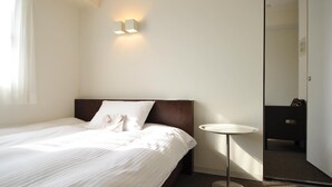 Et hotelværelse med en seng, et natbord og et spejl.