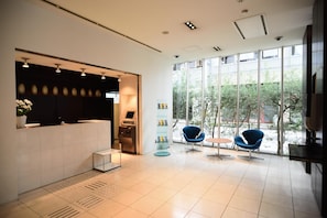 Un área de recepción moderna con mostrador, quiosco de autoservicio y asientos con vistas al exterior.