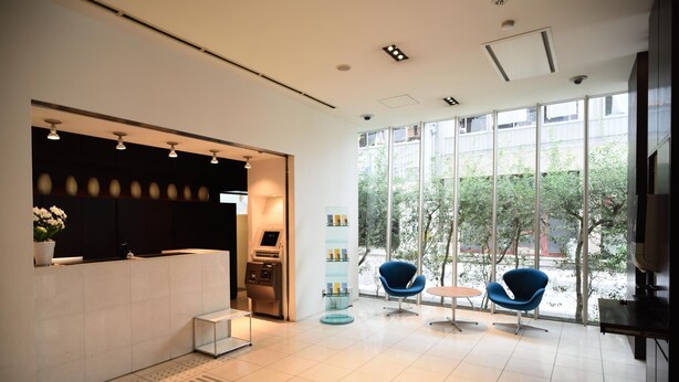Un área de recepción moderna con mostrador, quiosco de autoservicio y asientos con vistas al exterior.