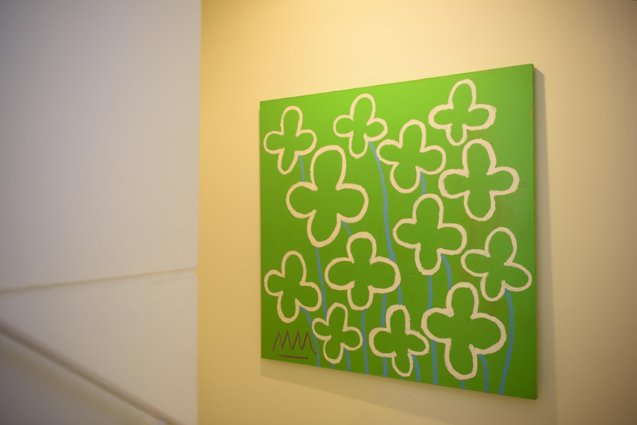 A green artwork with white clover designs on a wall.