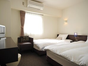A hotel room with two beds, a desk, a chair, an air conditioner, and a window with curtains. - 7days Hotel Plus (Kochi)