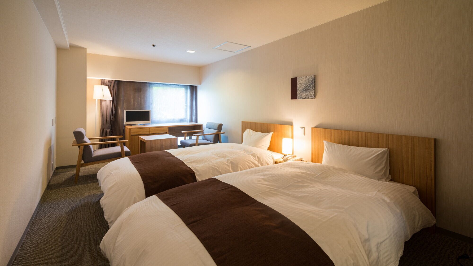 Une chambre d’hôtel avec deux lits, un bureau, une chaise, une télévision et une fenêtre.