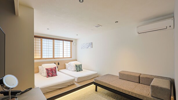 A hotel room with a bed, a sofa, a vanity with a mirror, and a window with blinds. - HOTEL FUJi TORiiGATE (Fujiyoshida)