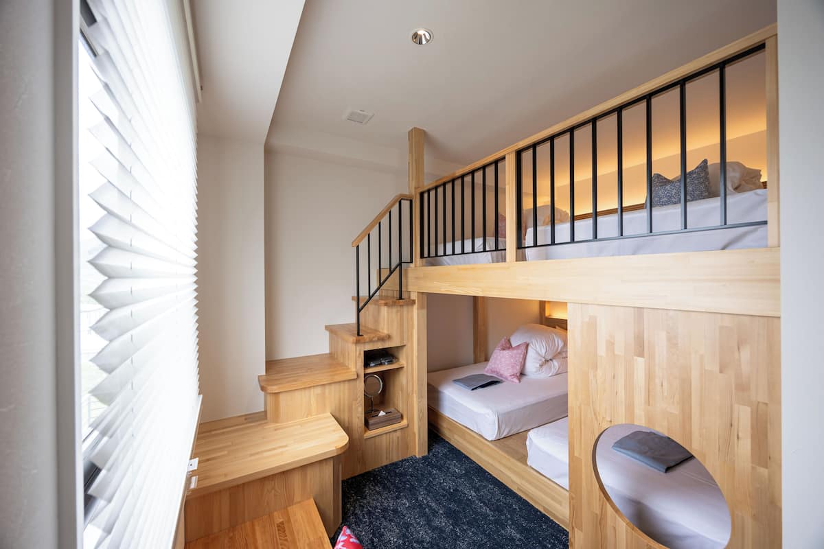 A compact room with a bunk bed, a desk, and a small seating area.