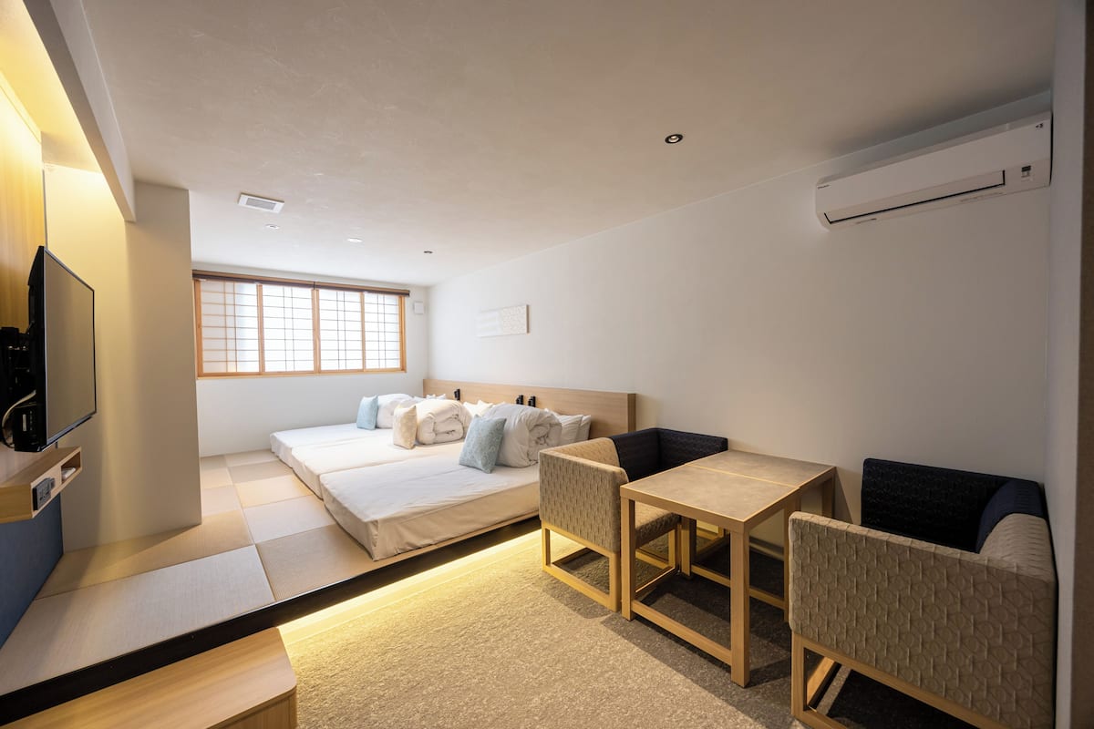 A modern hotel room with a bed, a desk, a chair, a TV, and a window.